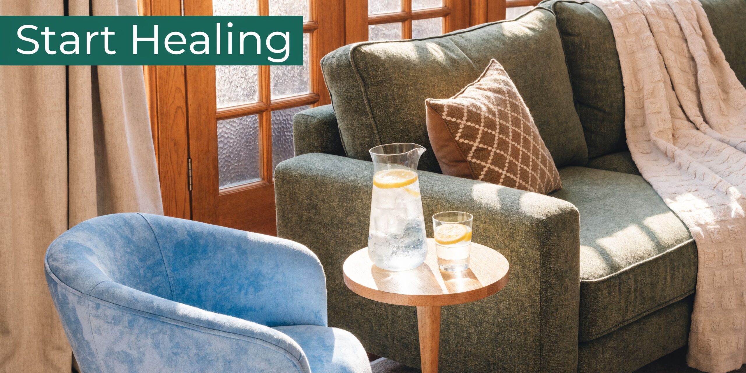 A cozy living room featuring a green sofa, a blue armchair, and a side table with water.