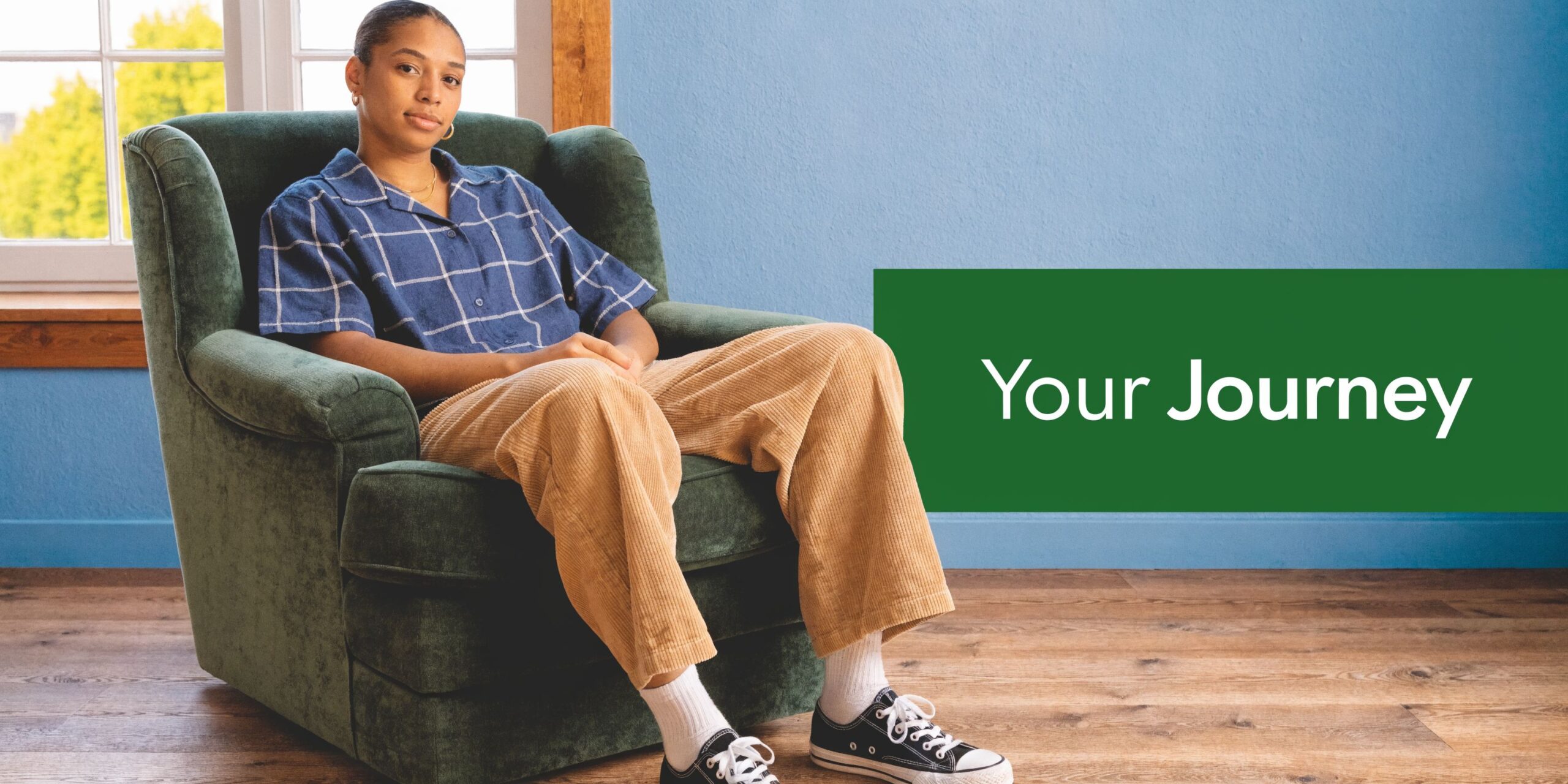 A person sitting comfortably in a green armchair looking towards the camera with a calm expression.