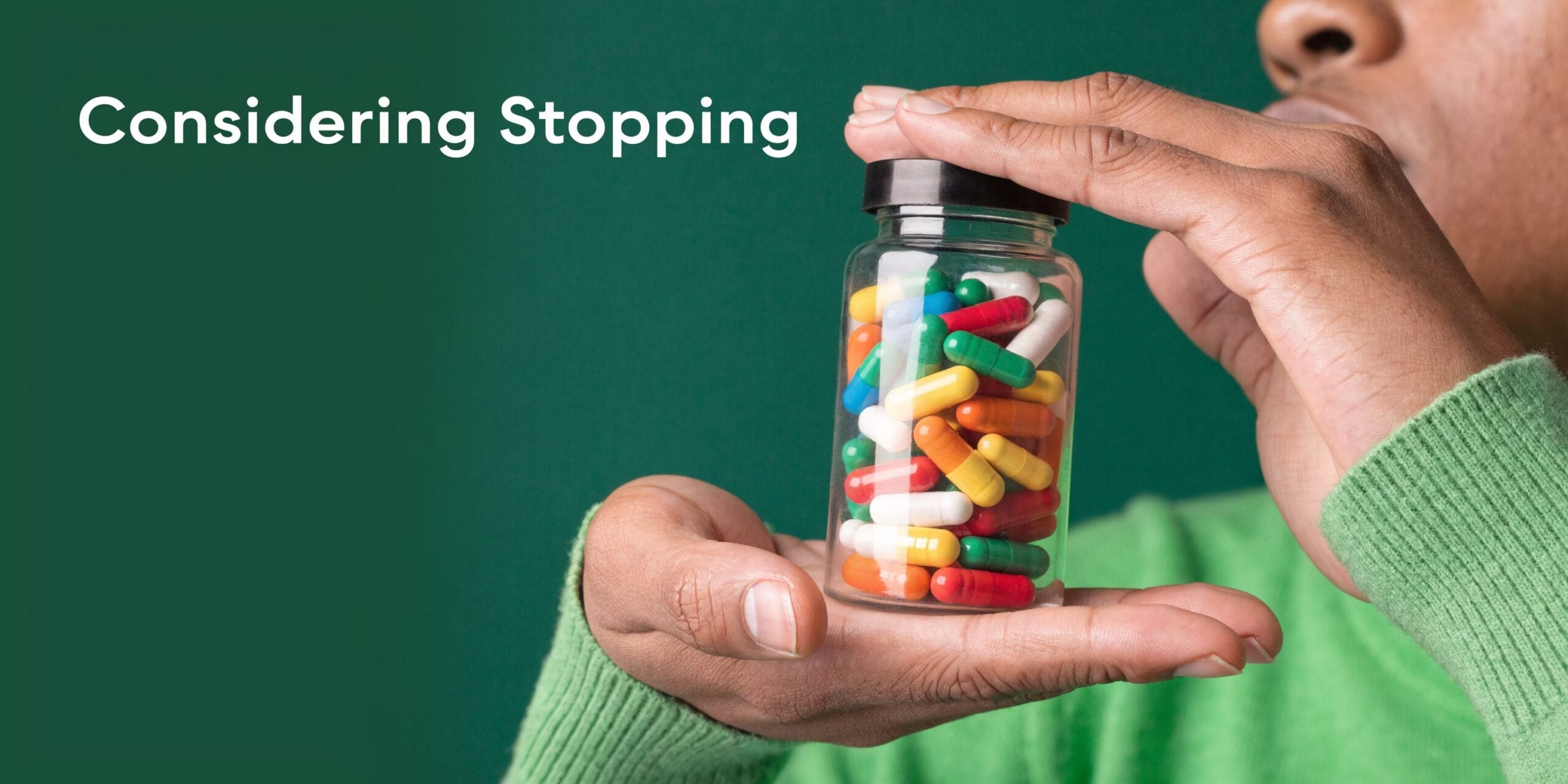 A person holding a bottle of colorful prescription medication while considering stopping their daily treatment.