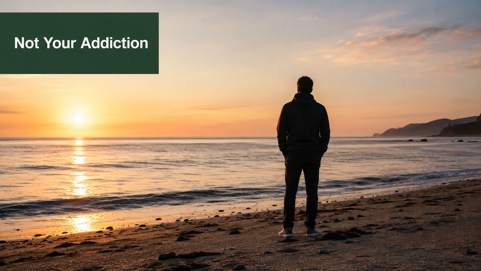 A person standing on a sandy beach at sunset, looking out at the ocean in contemplation.